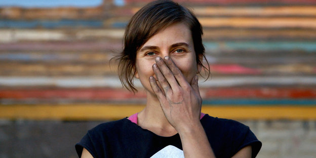 Eine Frau im T-Shirt hält sich die linke Hand vor den Mund
