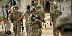 Ein paar US-Soldaten in Uniformen, teilweise bewaffnet, mit wenigen afghanischen Zivilisten