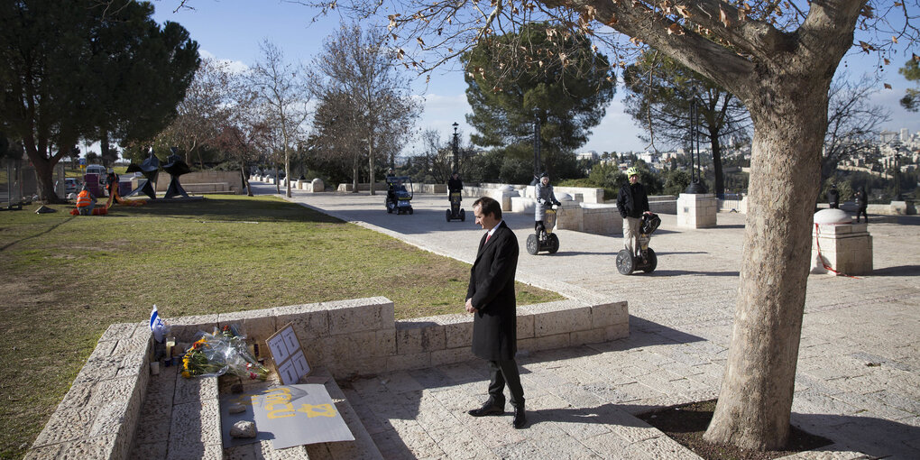 Ein Mann in schwarzem Mantel steht mit gefalteten Händen an der Stelle, an der ein LKW in Jerusalem in eine Gruppe Soldaten fuhr