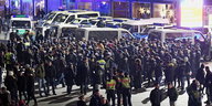 eine Menschenmenge und Polizisten, im Hintergrund Polizeifahrzeuge