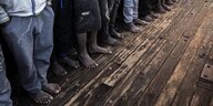 Beine von Menschen, die auf einem Holzboot stehen