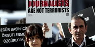 Ein Mann und eine Frau halten ein Plakat mit der Aufschrift "Journalists are not terrorists!"