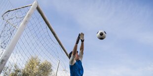 Torwart springt vor dem Tor einem anfliegendem Ball entgegen