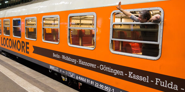 Ein orangener Zug am Gleis