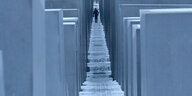 Blick durch die Stelen des Holocaust-Denkmals in Berlin. Im Hintergrund geht ein Mann.