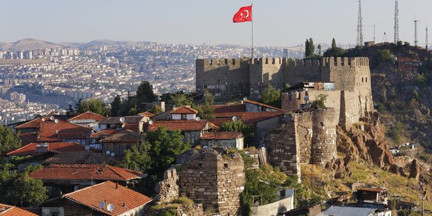 Blick auf eine Burg mit einer türkischen Flagge und ein tiefes Tal darunter