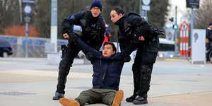 Polizisten tragen einen protibetischen Demonstranten