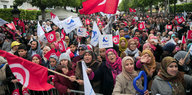 Eine Menschenmenge protestiert mit wehenden Fahnen, meist Nationalflaggen Tunesiens