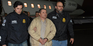 El Chapo in beiger Jacke wird von zwei Agenten abgeführt