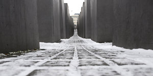 Zwischen den Stelen des Holocaust-Mahnmals in Berlin liegt Schnee