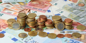Euromünzen liegen in Stapeln auf Euroscheinen