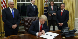 US-Präsident Trump unterschreibt auf einem Blatt Papier