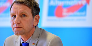 Björn Höcke sitzt vor einem AfD-Plakat