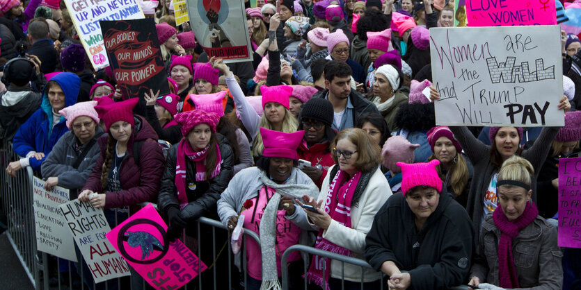 In einer Menschenmenge tragen viele pinke Mützen