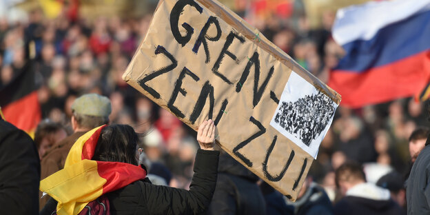 Bei einer Pegida-Demonstration in Dresden hält eine Person einen Pappkarton mit der Aufschrift "Grenzen zu!"