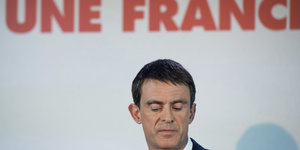 Manuel Valls blickt zu Boden, über im der Schriftzug „Une France“