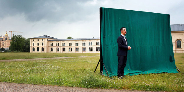 Cem Özdemir steht für die Fotografen vor einem grünen Tuch auf einer Wiese in Schwerin