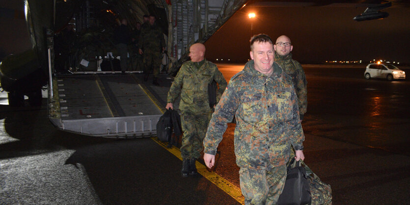 Oberstleutnant Christoph Huber steigt mit Soldaten aus einem Flugzeug