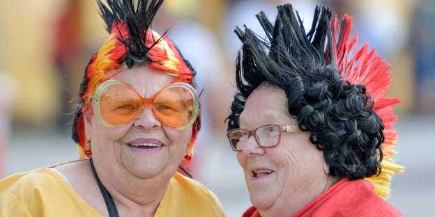 Zwei Frauen mit schwarz-rot-goldenem Kopfschmuck