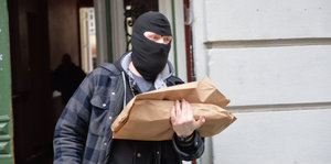 Ein maskierter Mann trägt ein Paket