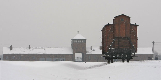 Ein hölzerner Eisenbahnwaggon steht vor dem Haupttor des KZ Auschwitz -Birkenau im Schnee