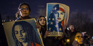 Frauen halten bei einer Demonstration Kerzen und Plakate von anderen Frauen hoch