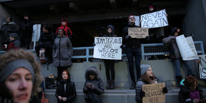 Menschen in New York halten Schilder hoch: Never Again und Immigrants are welcome here, steht darauf