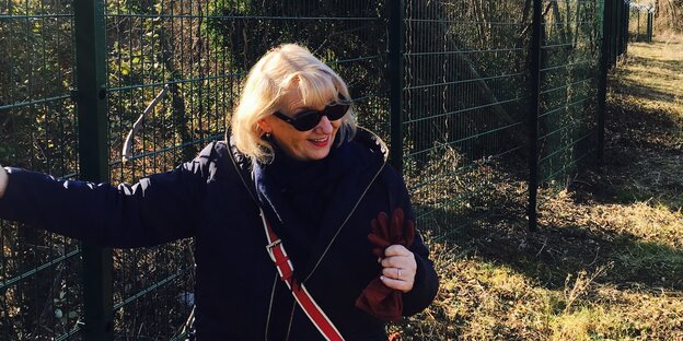 Eine Frau steht an einem Zaun Eine Frau steht an einem Zaun