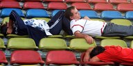Menschen schlafen auf Stadionbänken