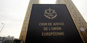 zwei Hochhaustürme, davor ein Schild mit der Aufschrift „Cour de Justice d L'Union Européenne“