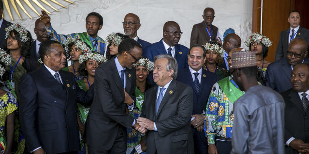 Männer in Anzügen und Frauen mit Blumen im Haar stehen als Pulk beim Gipfel der Afrikanischen Union herum