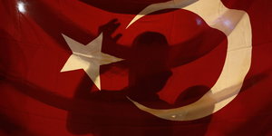 eine türkische Flagge, auf der sich die Silhouette einer Person abzeichnet