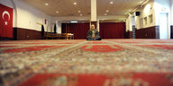 Ein Mann sitzt in einer Moschee auf Teppichen