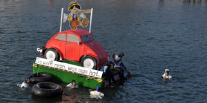 Das Modell eines VW-Käfers schwimmt auf einem Floß in einem Fluss
