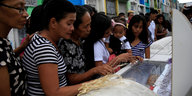 Philippinische Frauen stehen am offenen Sarg eines Mannes
