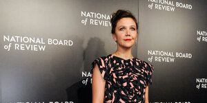 Die Schauspielerin Maggie Gyllenhaal steht vor einer Wand, an der mehrfach "National Board of Review" steht