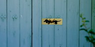 Auf einer blauen Holzwand ist ein Schild mit einem durchgestrichenen Dackel
