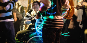 Eine Frau im Rollstuhl feiert gemeinsam mit Menschen ohne Behinderung im Mensch Meier