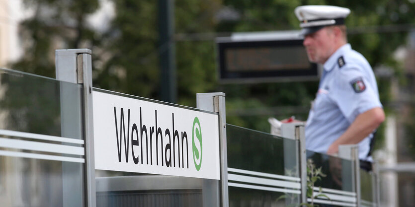 Ein Polizist steht neben einem Schild, auf dem "Wehrhahn" steht