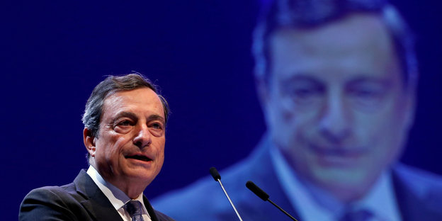 Mario Draghi an einem Rednerpult, im Hintergrund ist er nochmal zu sehen