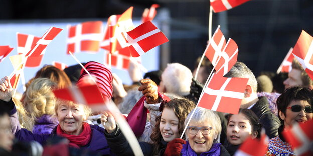 Fröhliche Menschen winken mit dänischen Fahnen