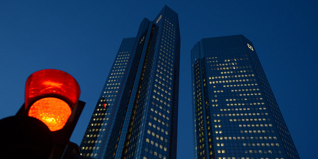 ein rotes Ampellicht vor der Zentrale der Deutschen Bank in Frankfurt/Main leuchtet in der Dämmerung