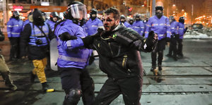 Ein Mann wird von einem Polizisten festgehalten