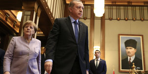 Erdogan schreitet voran, blickt nach links, rechts hinter ihm Kanzlerin Angela Merkel