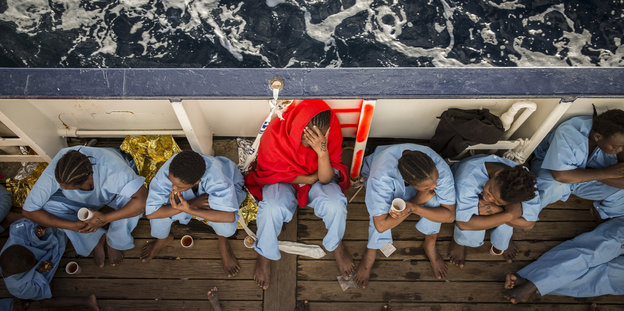 Frauen in blauer Kleidung sitzen an Deck eines Schiffes