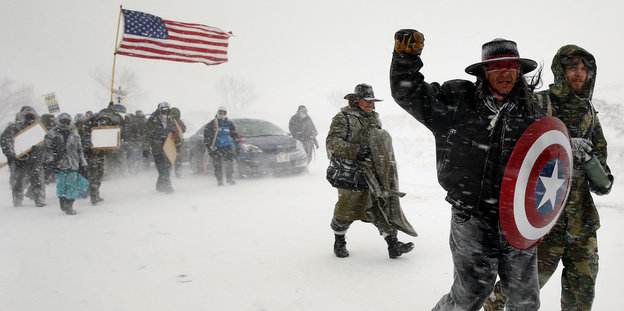 Menschen demonstrieren mit einer US-Flagge in vielen Schnee