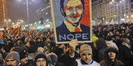 Eine Menge Demonstranten, einer von ihnen hält ein Schild hoch, auf dem Liviu Dragnea zu sehen ist