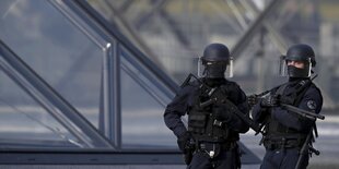 Zwei schwer bewaffnete Polizisten bewachen das Areal vor dem Eingang zum Louvre