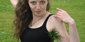 Frau auf Wiese mit Gras unter der Achsel