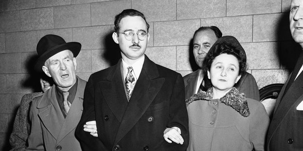 Julius und Ethel Rosenberg sind auf einer schwarz-weiß Fotografie zu sehen. Er trägt Handschellen, sie hat sich bei ihm untergehakt